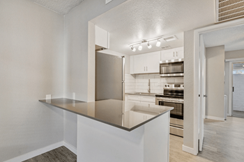 A kitchen with a stainless steel refrigerator and white cabinets at Tides on East Cactus Apartments, AZ